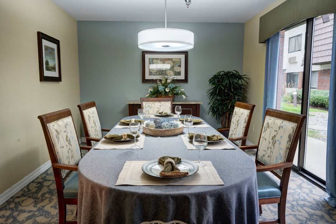 A well-decorated dining room with a round table set for a meal, featuring a chandelier and elegant decor.