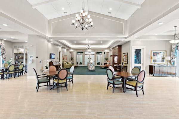 A spacious and elegantly furnished lobby with tables, chairs, and a chandelier.