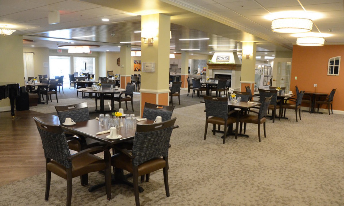 A spacious dining area with neatly arranged tables and chairs, well-lit with warm lighting.