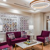 A modern and elegant living room with purple seating, stylish lighting, and decorative elements.
