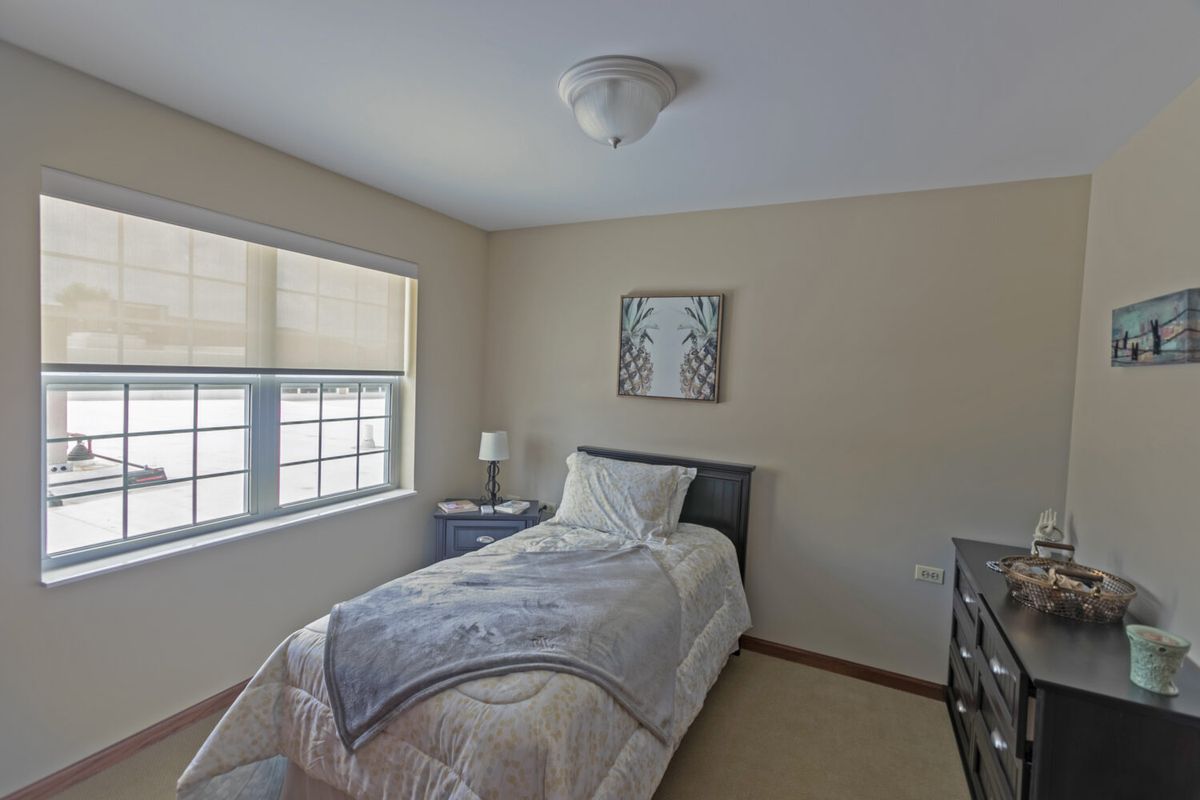 A minimalist bedroom with a single bed, nightstand, and decorative artwork.