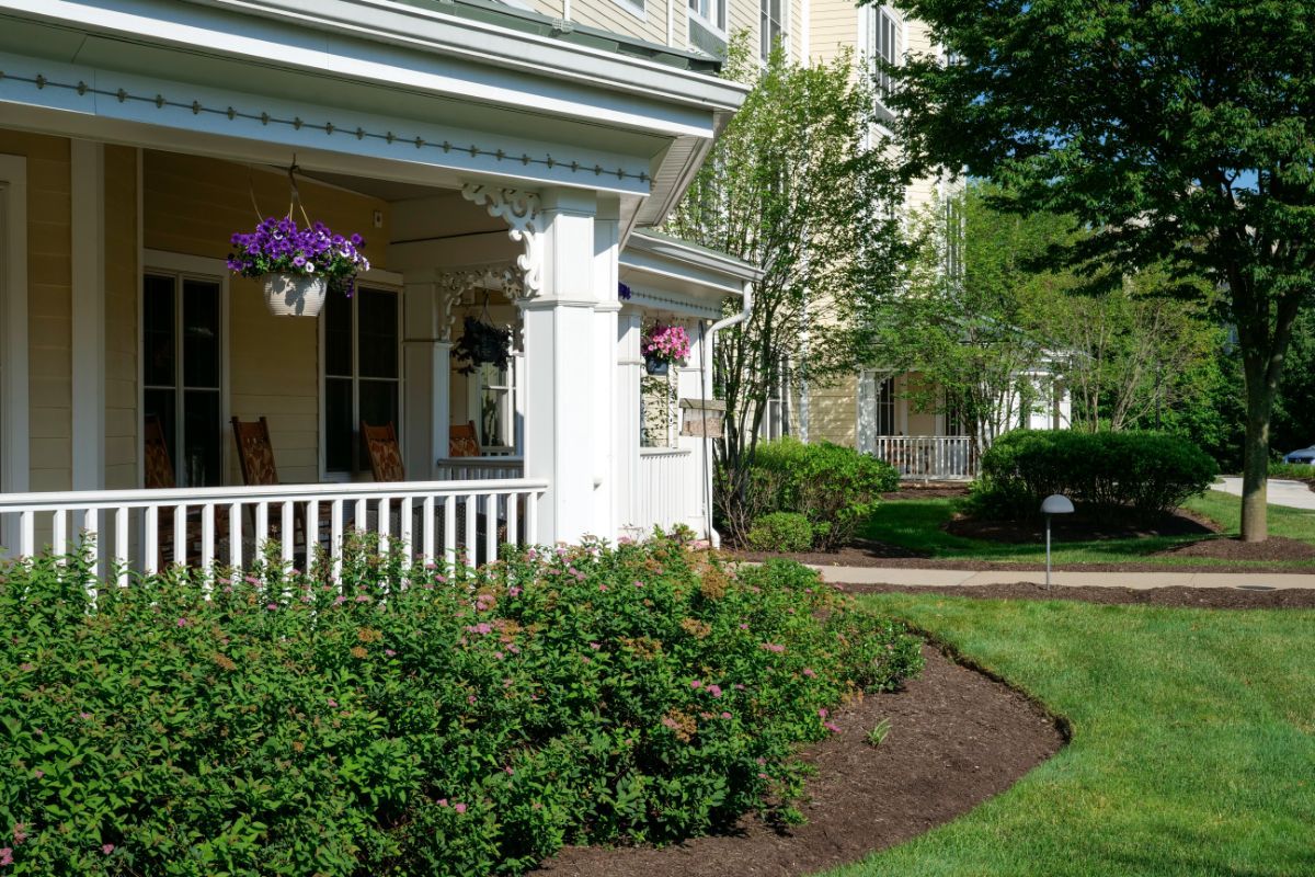 A charming house with a front porch and well-maintained garden, featuring flowers and shrubs.