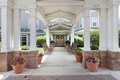 A covered entrance with columns and potted plants lining the walkway.