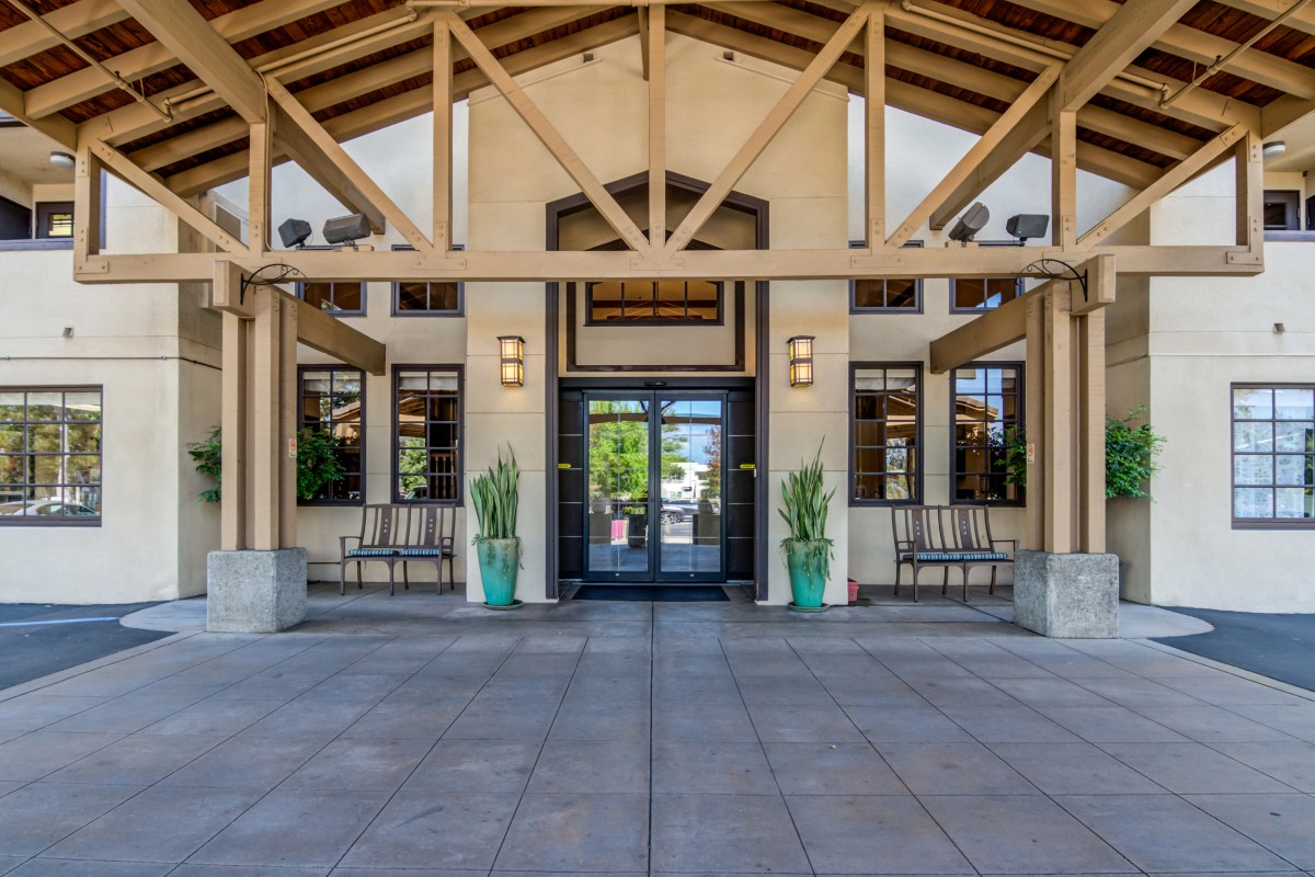 A building entrance with plants and outdoor seating.