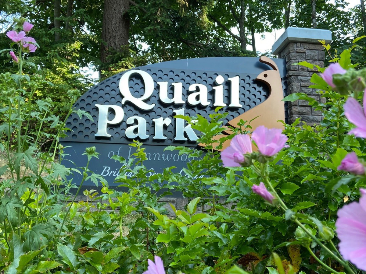 Entrance sign for Quail Park surrounded by lush greenery and flowers.
