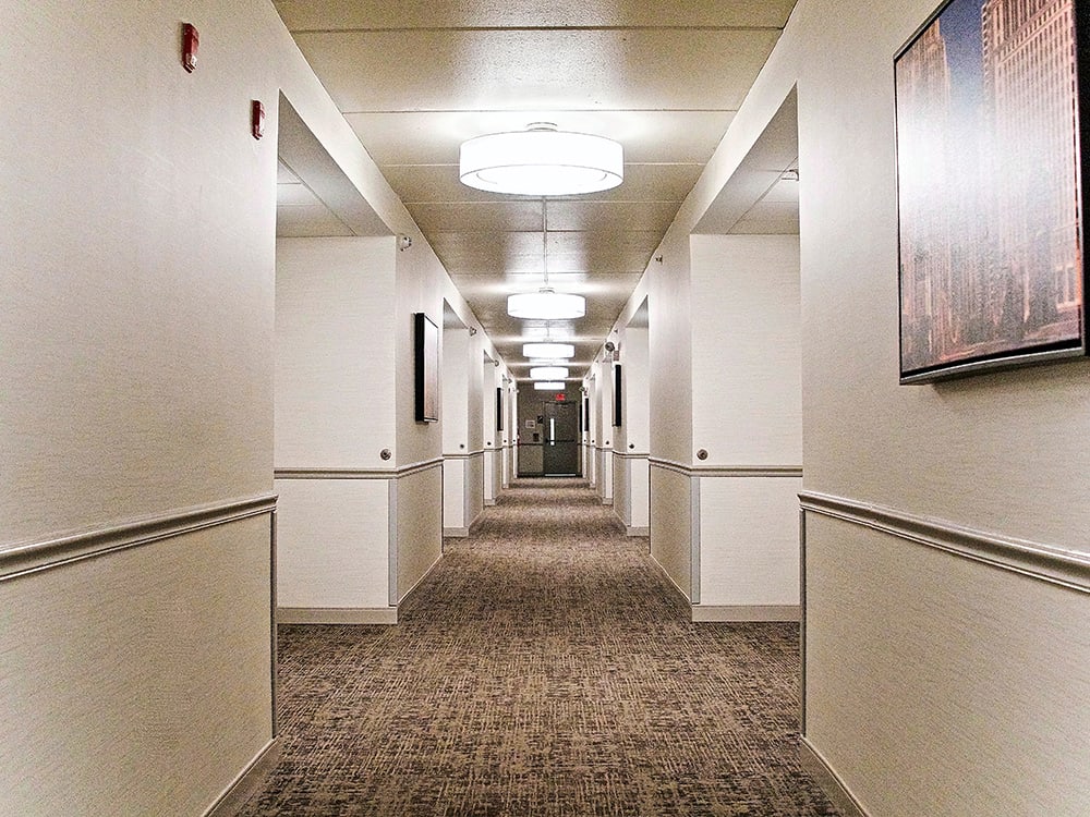 A well-lit, symmetrical hallway with carpeted flooring and ceiling lights.