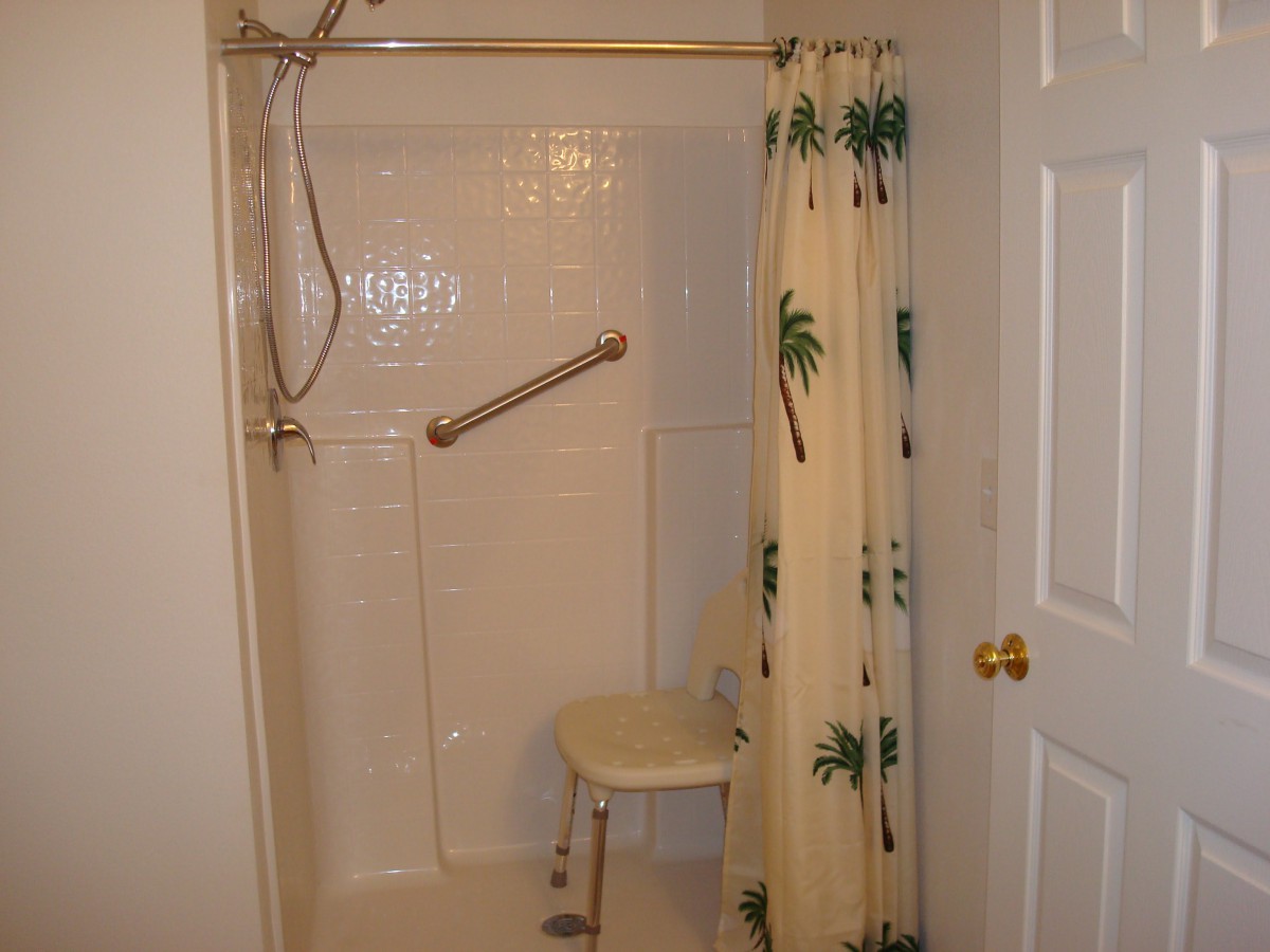 An accessible bathroom shower equipped with a grab bar and shower chair.