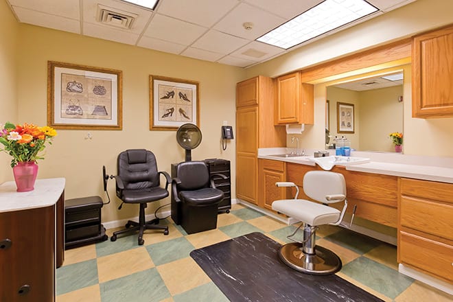 A well-equipped salon room featuring chairs, a mirror, and styling equipment.