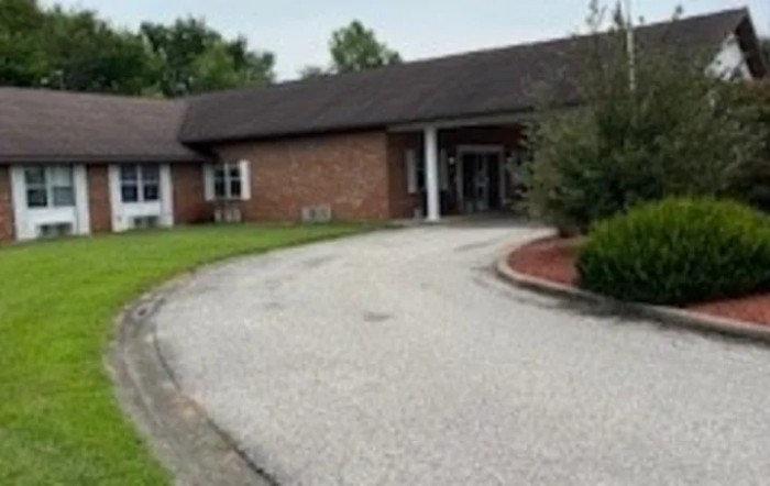 A brick building with a driveway and landscaped entrance.