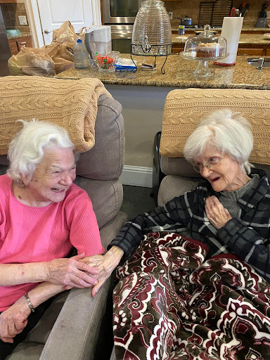 Two elderly friends share a joyful moment together, highlighting the beauty of companionship in their golden years.