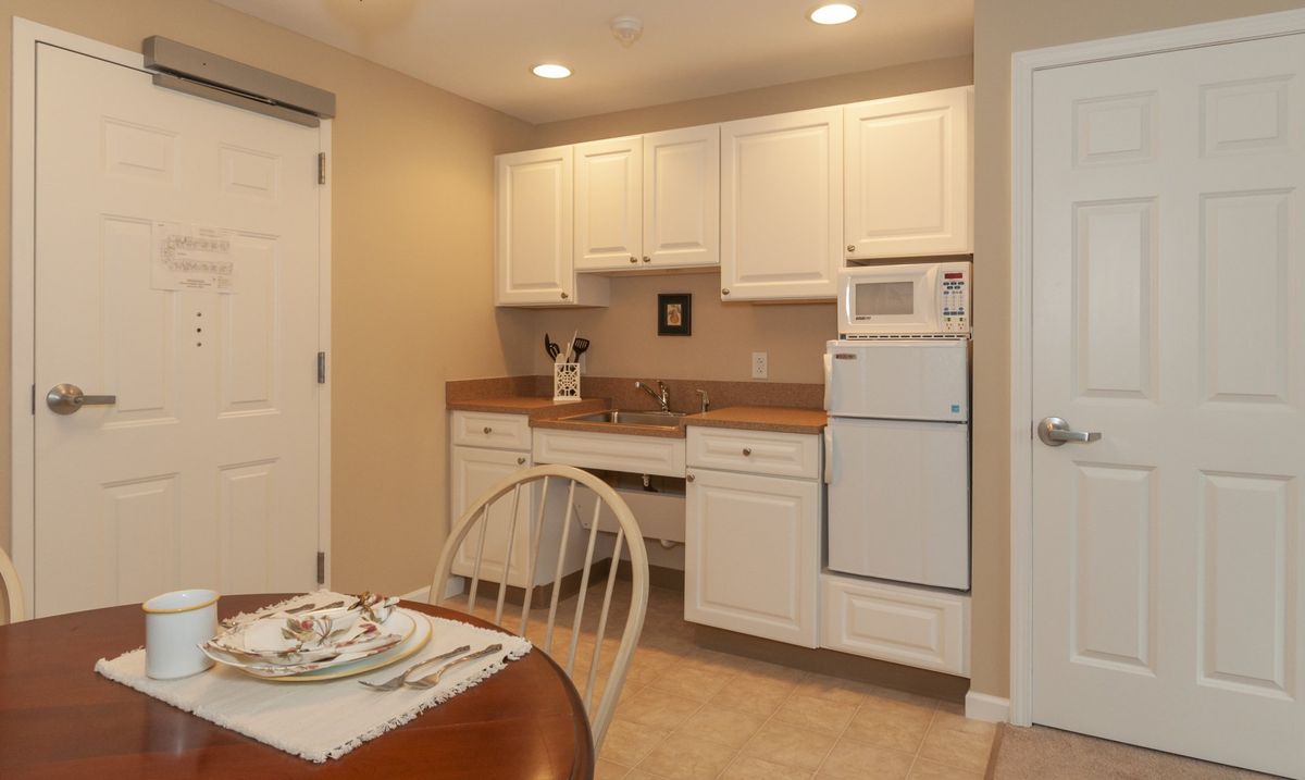 A small kitchen area with white cabinets and a dining table set.