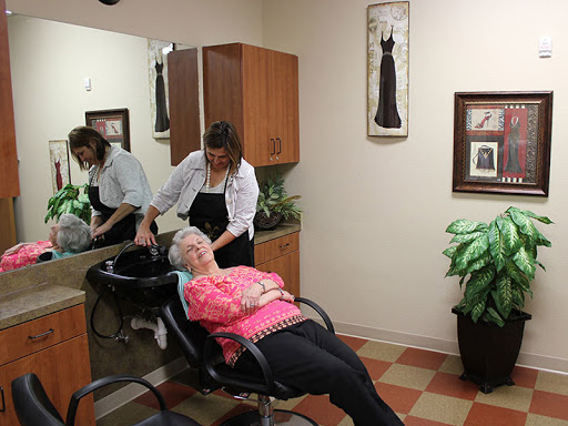 A hairstylist provides a hair treatment to an elderly woman in a cozy salon environment.