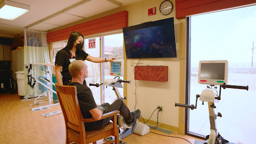 A rehabilitation session where a patient engages in exercise while watching a television screen, guided by a healthcare professional.
