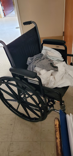 An unused wheelchair with some clothing draped over it.