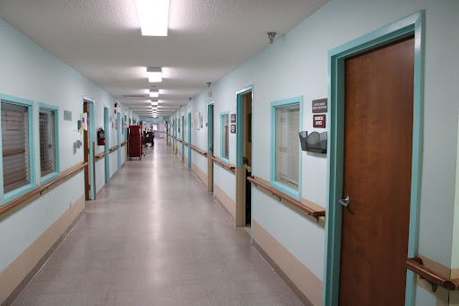 A quiet corridor in a healthcare facility, featuring blue walls and multiple doors.