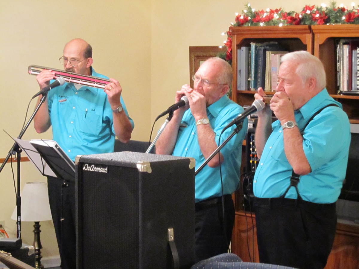 A group of musicians performing with harmonicas indoors.