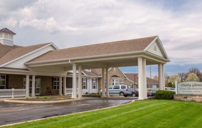 A hotel entrance with a covered driveway and parked cars.