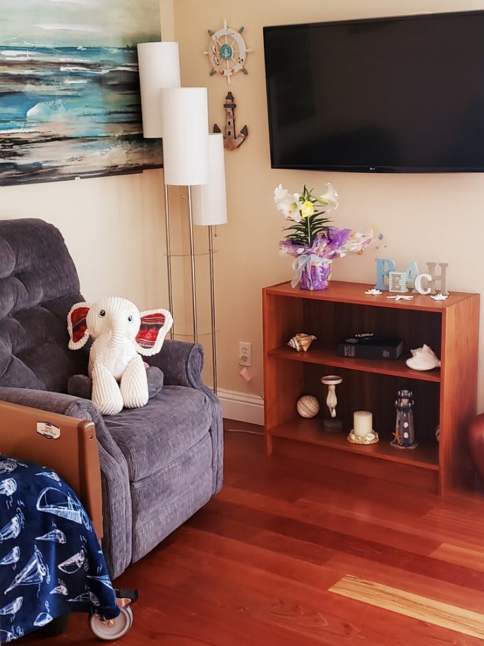 Cozy living room corner with a plush chair, stuffed elephant, and a small bookshelf.