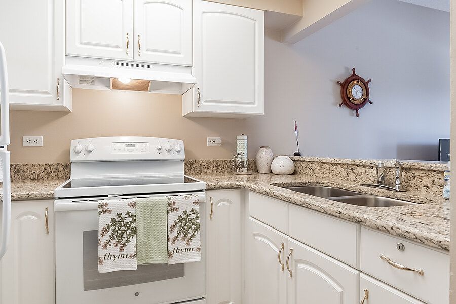 A modern kitchen with white cabinets and a granite countertop.