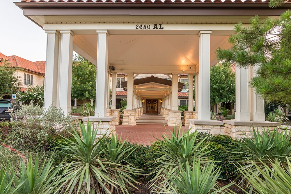 A building entrance with columns and landscaped garden.