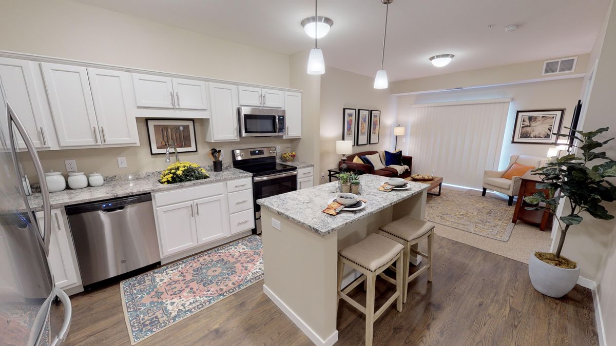 A modern open-concept kitchen and living area with an island counter and stainless steel appliances.
