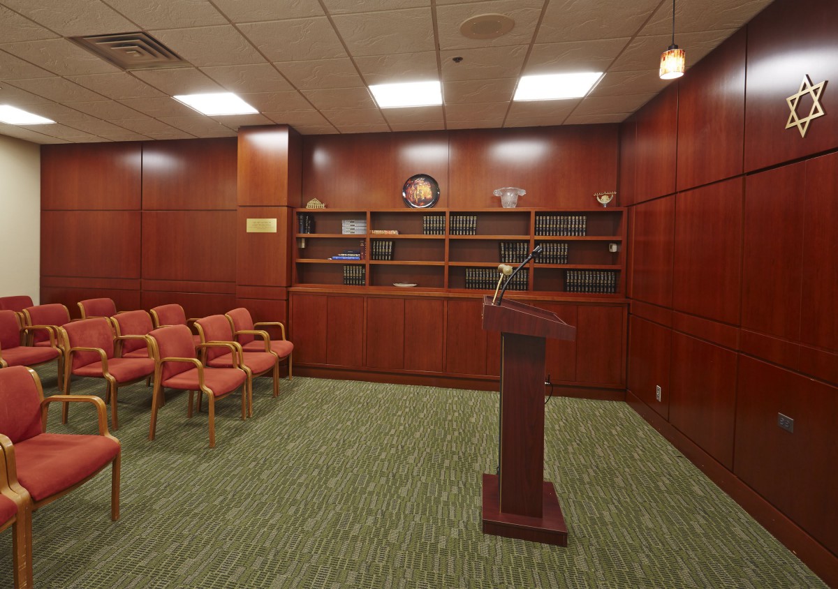 A small conference room with a podium, chairs, and bookshelves lined against wood-paneled walls.