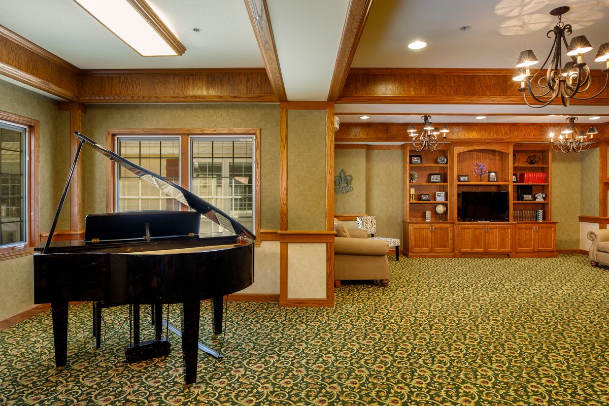 A cozy living room with a grand piano and elegant wood paneling.