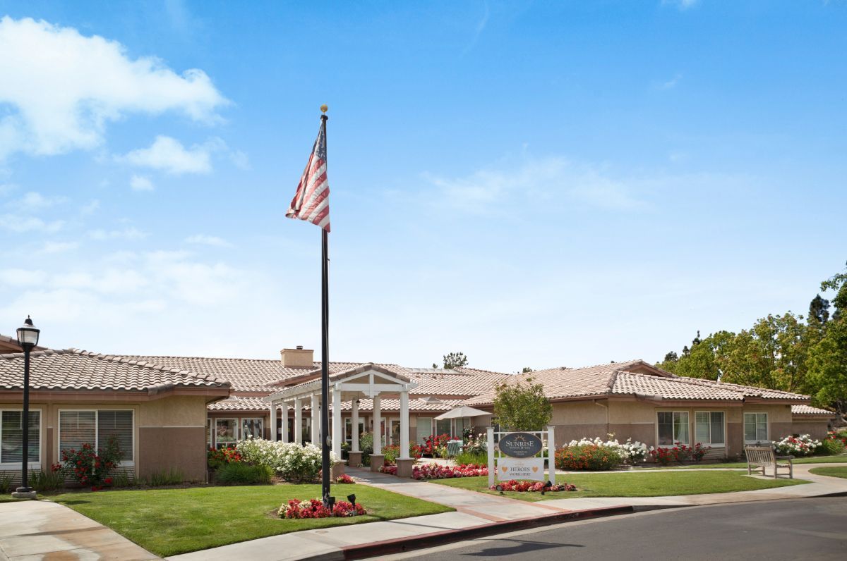 A well-maintained residential building with a flagpole in front on a sunny day.