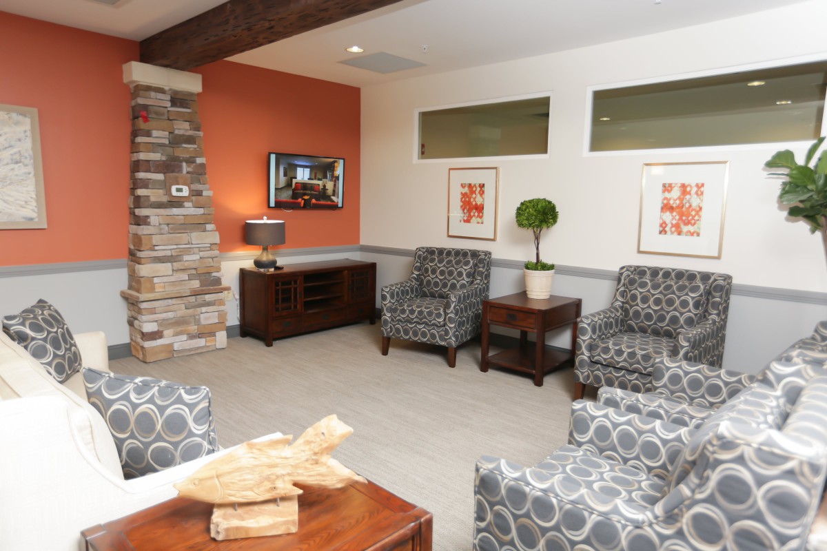 A cozy living room with patterned chairs, a wooden table, and decorative artwork.