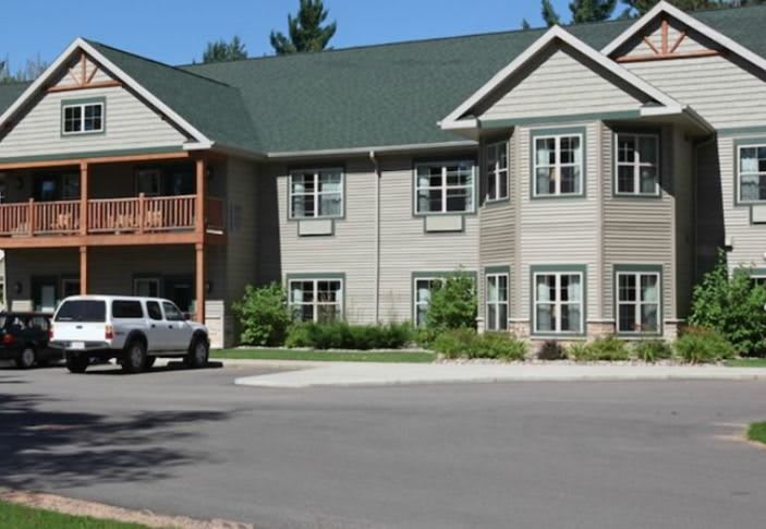 A two-story residential apartment building with a parking lot in front.