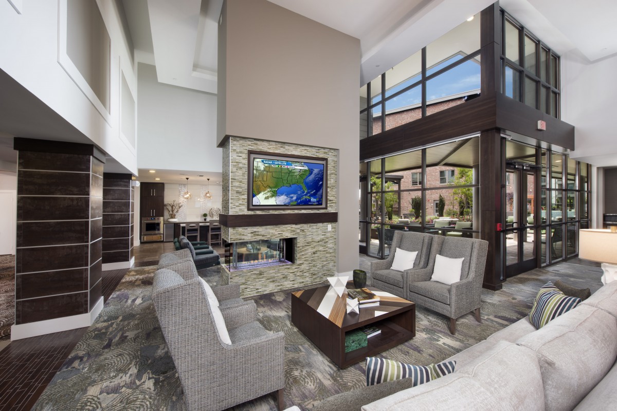 A modern living room featuring a fireplace, large windows, and stylish furniture.