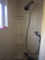 A modern shower setup with a detachable showerhead and built-in shelves.