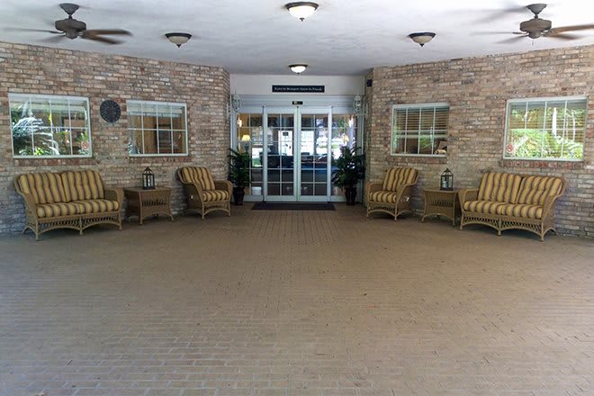 A building entrance with seating arrangements and a brick wall.