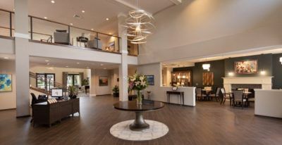 A stylish and modern lobby with a central table adorned with flowers, featuring a striking chandelier and contemporary decor.