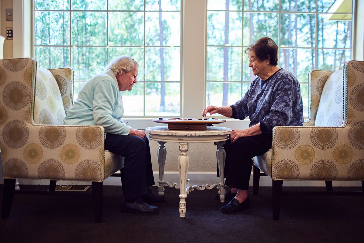 Two seniors playing a board game by the window.