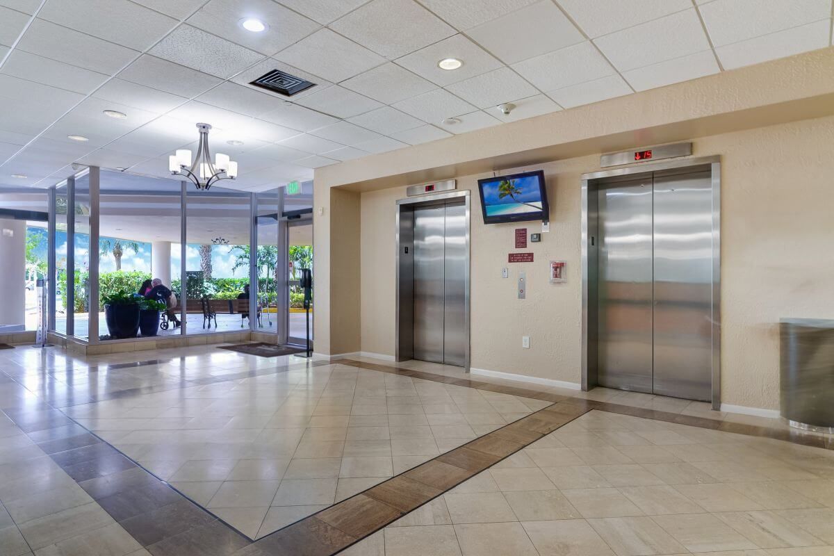 Spacious hotel lobby with elevators and a view of the entrance.