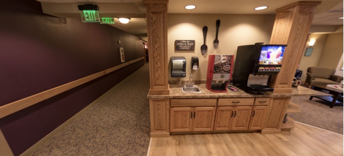 A hallway with a coffee station featuring wooden cabinets and decorative utensils on the wall.