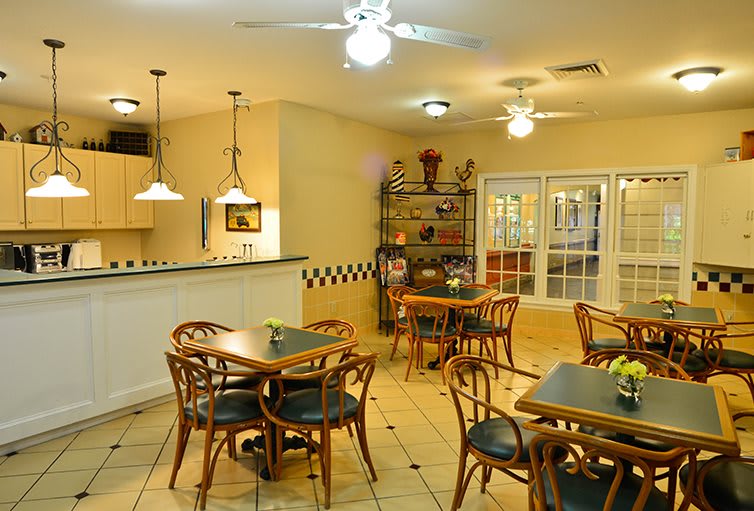 A cozy dining area with wooden tables and chairs, ceiling fans, and warm lighting.