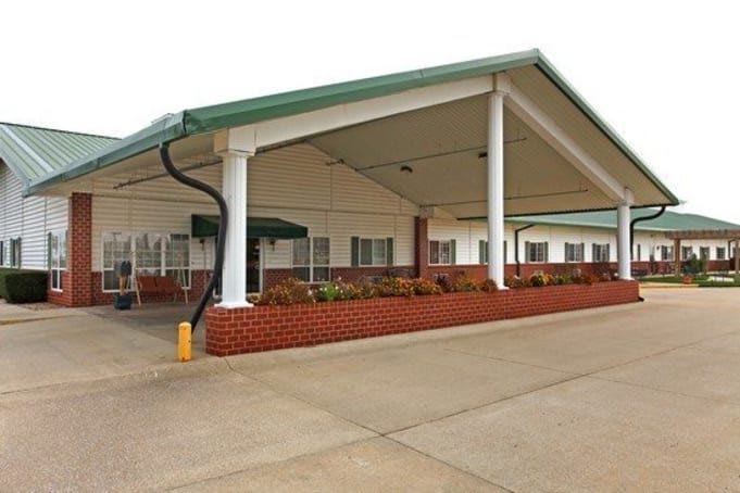 The image shows the entrance of a motel with a covered driveway and brick facade.
