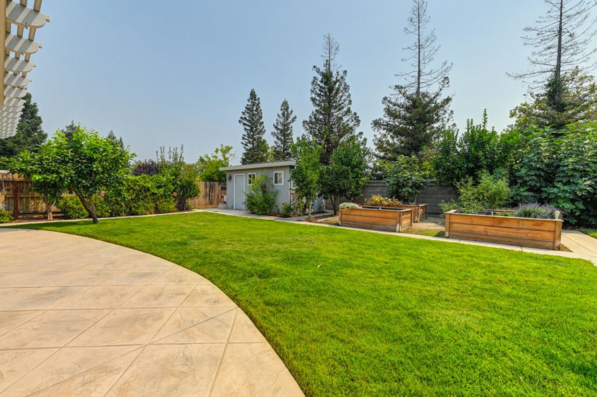 A backyard with a well-maintained lawn, trees, and a garden area.
