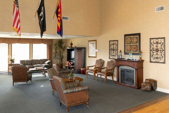 A spacious living room with comfortable seating, a decorative fireplace, and flags on display.