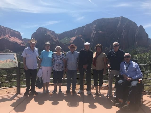 A group of people posing in front of a mountainous landscape on a sunny day.