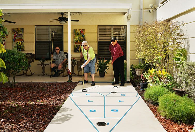 Seniors enjoying a game of shuffleboard on a patio.