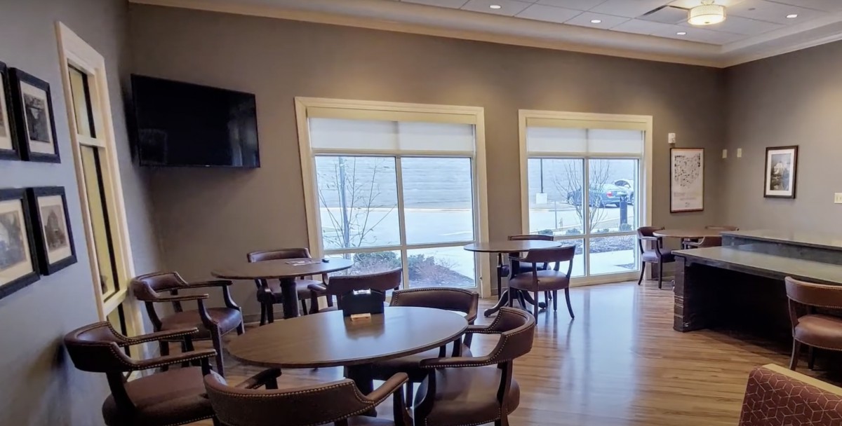 A well-lit dining area with several tables and chairs, featuring large windows that let in natural light.