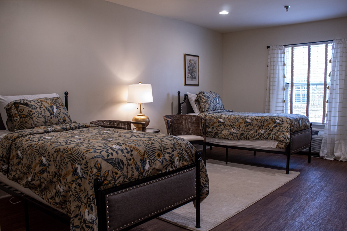 A cozy bedroom with two twin beds and a bedside lamp.