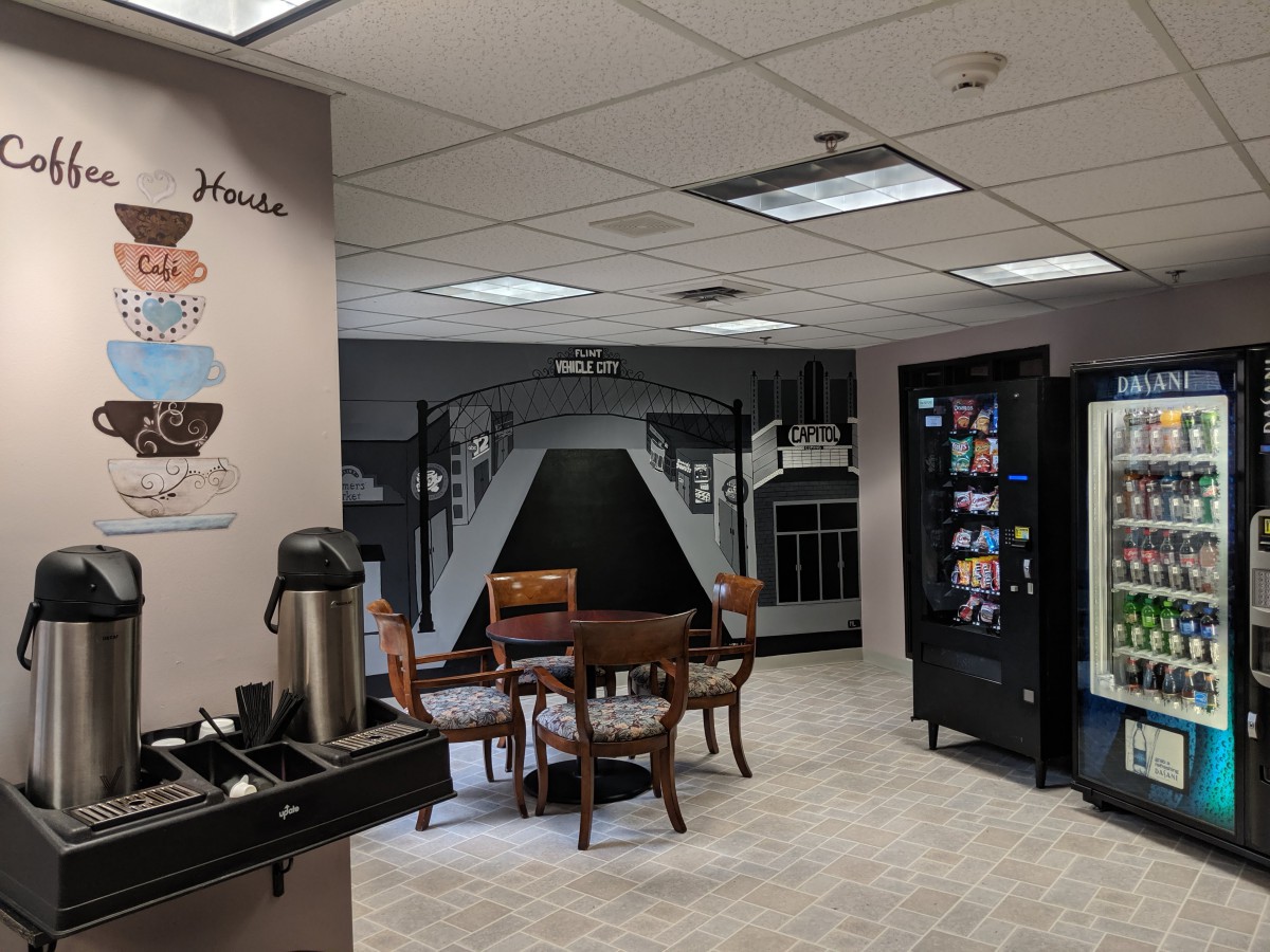 A break room featuring a coffee station, vending machines, and a seating area with tables and chairs.
