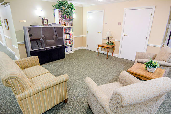 A cozy living room with comfortable seating, a large television, and a bookshelf.