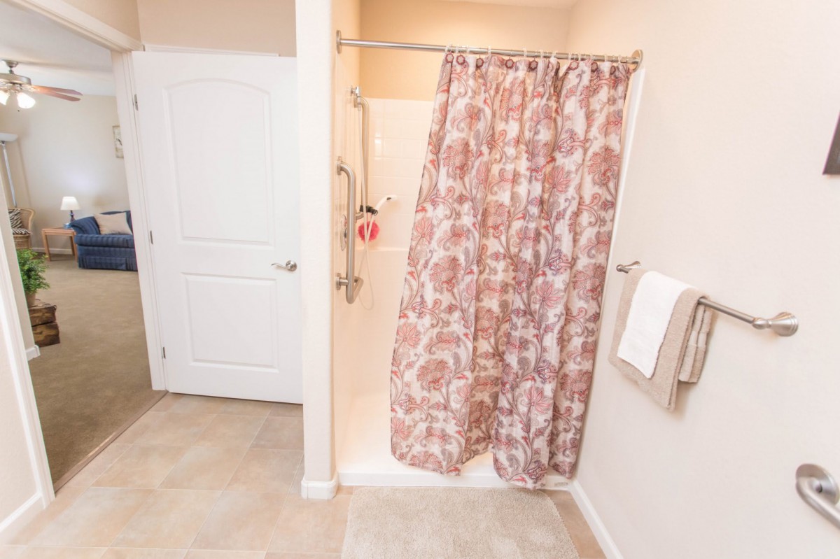A cozy bathroom featuring a shower with a floral-patterned curtain and a tiled floor.