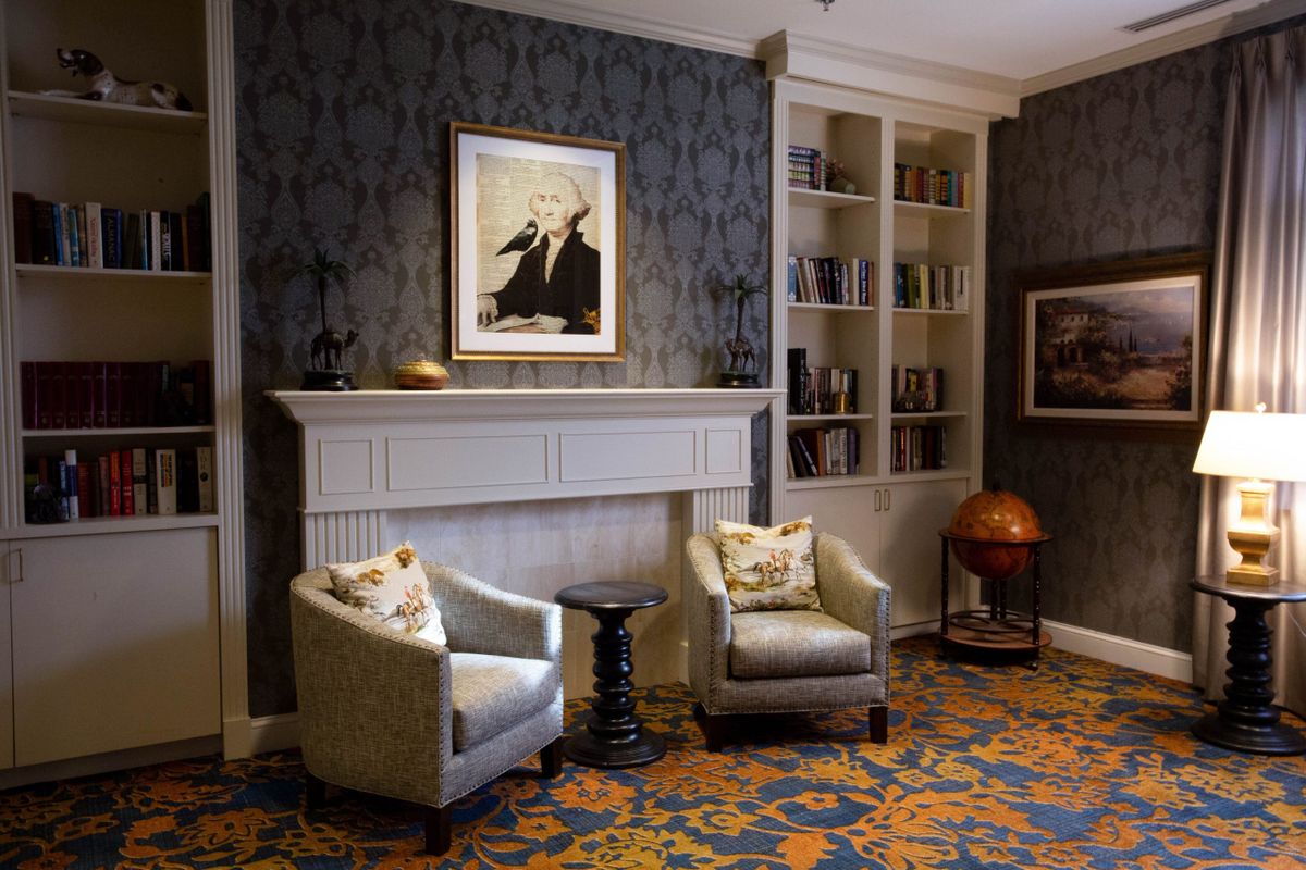 A cozy living room with a fireplace, two armchairs, and a bookshelf.