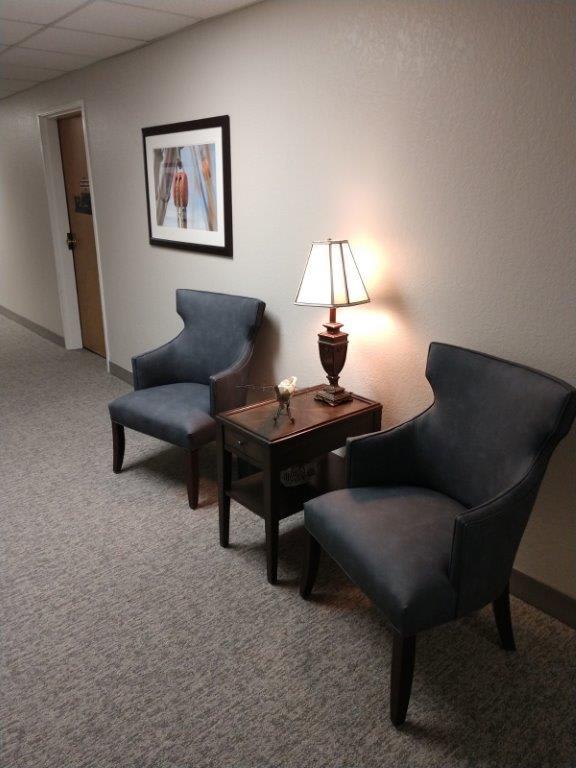 A hallway with two chairs, a small table, and a lamp.
